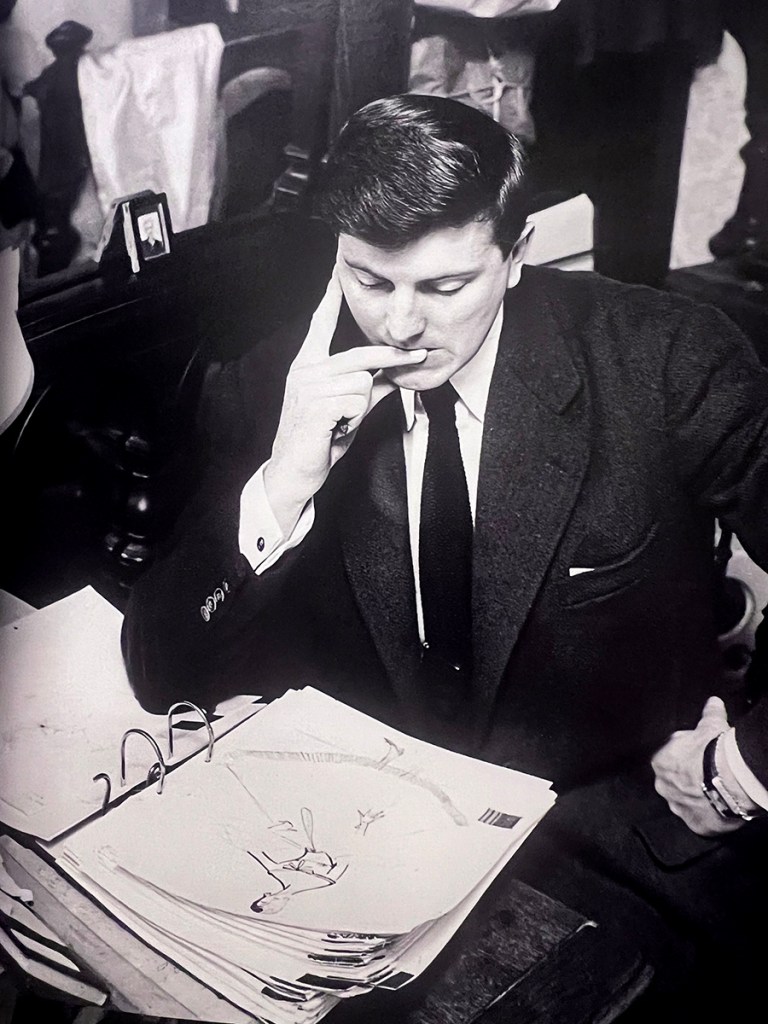Hubert de Givenchy, alos veinticinco años, examinando sus bocetos en su despacho de la Rue Alfred de Vigny en París.